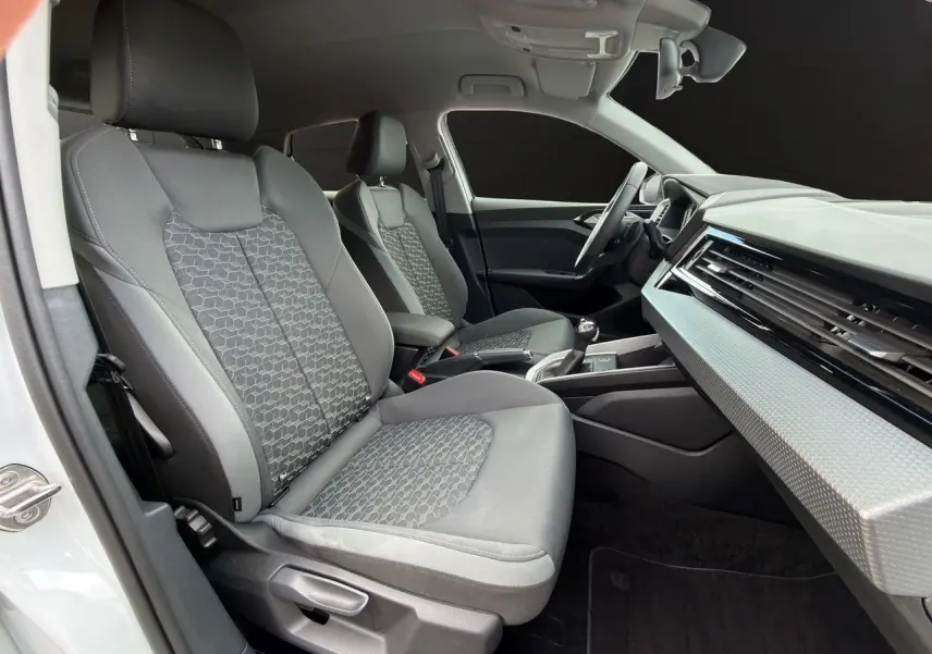 Vue intérieure côté conducteur de l'Audi A1 Sportback 2025 avec sièges gris et tableau de bord moderne.