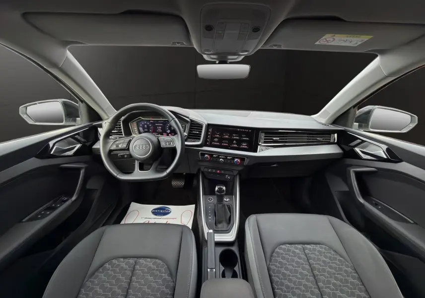 Vue intérieure avant de l'Audi A1 Sportback 2025 avec tableau de bord numérique et sièges noirs.