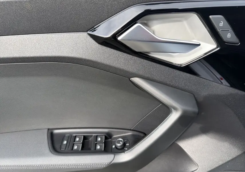 Détail de la porte intérieure côté conducteur de l'Audi A1 Sportback 2025 avec commandes de vitres et poignée argentée.