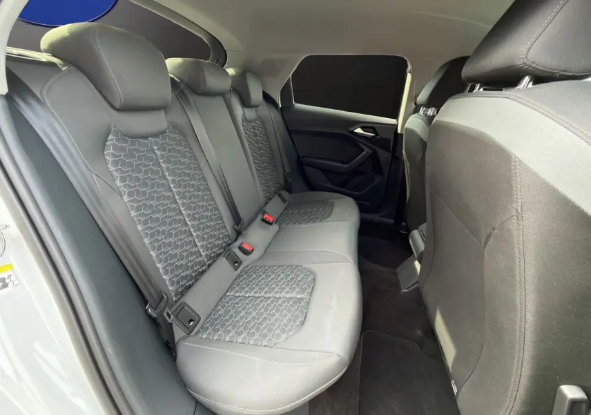 Vue intérieure côté gauche des sièges arrière gris à motifs hexagonaux de l'Audi A1 Sportback blanche 2025.