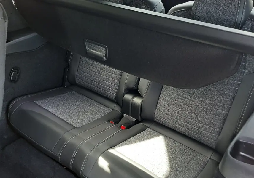 Vue intérieure arrière du Peugeot 5008 Hybrid 145ch Allure 2025, montrant les sièges gris tissu et cuir avec cache-bagages déployé.