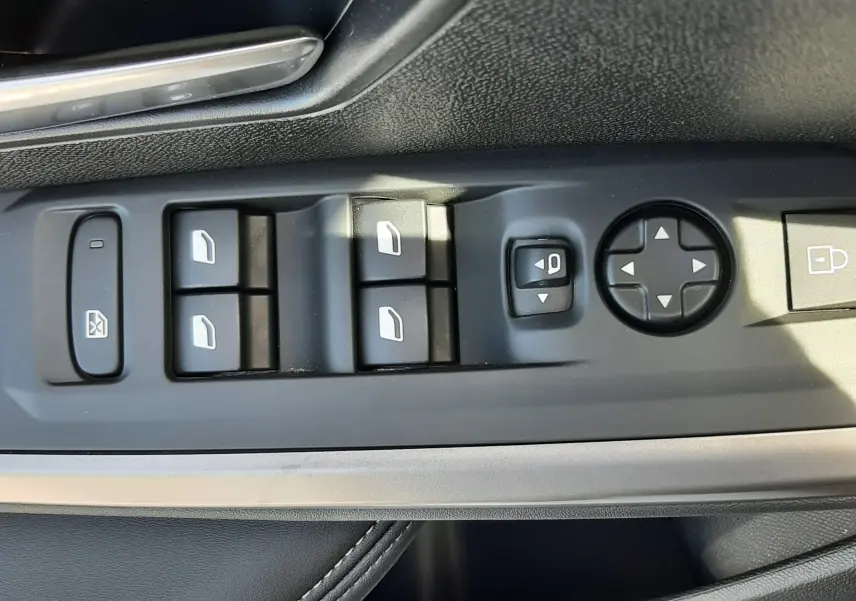 Gros plan sur la commande des vitres et rétroviseurs côté gauche intérieur d’un Peugeot 5008 gris Artense 2025.