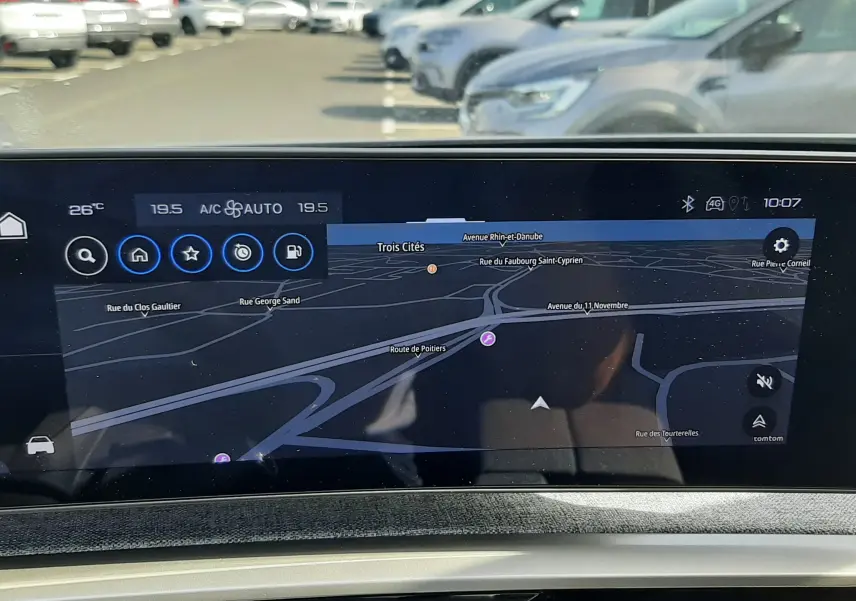Vue rapprochée de l'écran tactile du tableau de bord du Peugeot 5008 gris Artense, affichant la navigation GPS en extérieur.