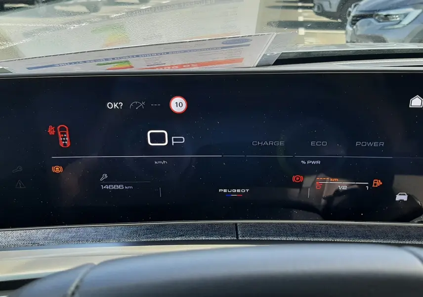Vue intérieure du tableau de bord numérique du Peugeot 5008 Hybrid gris, affichant la vitesse à zéro et l'autonomie restante.