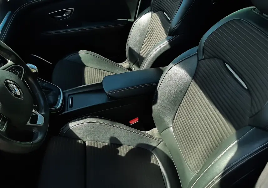 Vue intérieure côté conducteur du Renault Scénic IV 2018, sièges en cuir noir avec surpiqûres blanches et volant multifonction.