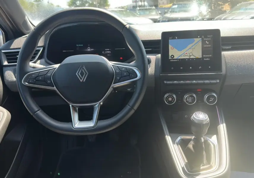 Vue intérieure centrée sur le volant Renault et la console centrale avec écran tactile et levier de vitesse manuel.