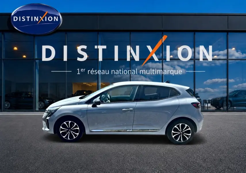Renault Clio V gris rafale vue de profil côté gauche devant une vitrine avec logo Distinxion.