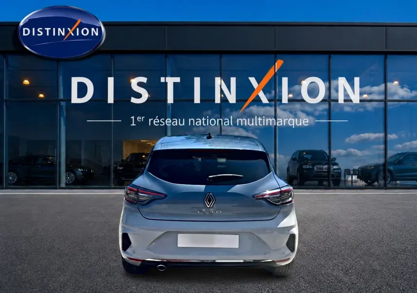 Vue arrière d'une Renault Clio V gris rafale garée devant une vitrine avec logo Distinxion.