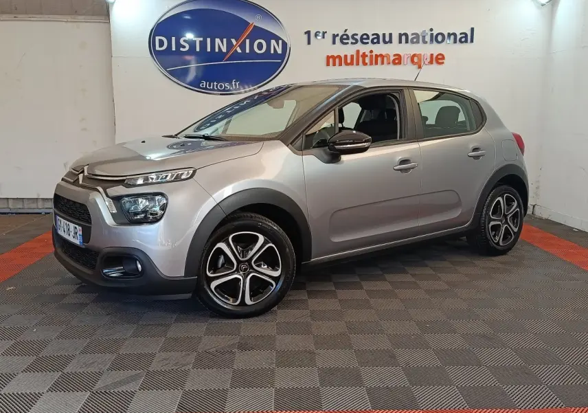 Citroën C3 gris foncé vue 3/4 avant droit, avec phares LED et jantes alliage distinctives en intérieur showroom.