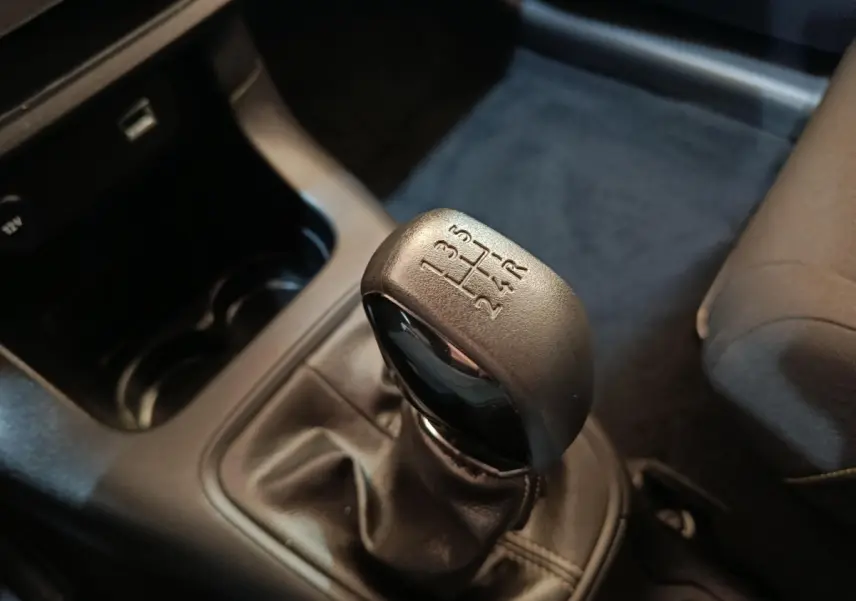 Gros plan sur le levier de vitesse manuel noir de la Citroën C3 PureTech 83 BVM PLUS, intérieur gris foncé.