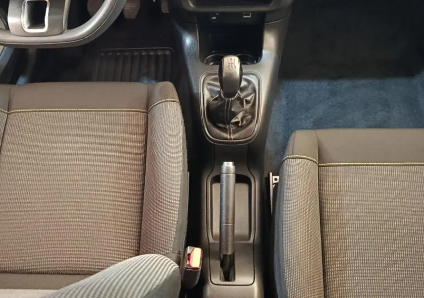 Vue intérieure centrée sur la console centrale et le levier de vitesse manuel de la Citroën C3 gris foncé 2024.