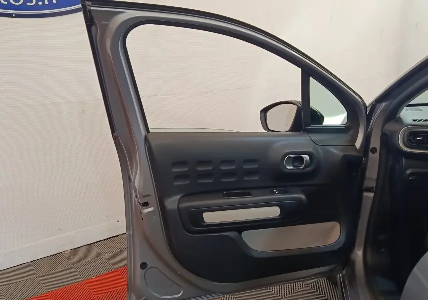 Vue intérieure de la porte avant gauche grise foncée d'une Citroën C3 2024 avec détails du panneau de porte noir et beige.