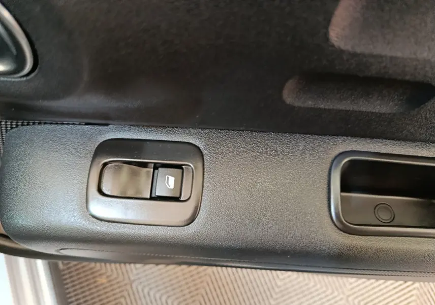 Gros plan sur le bouton de commande de la vitre côté conducteur d'une Citroën C3 gris foncé, intérieur noir.