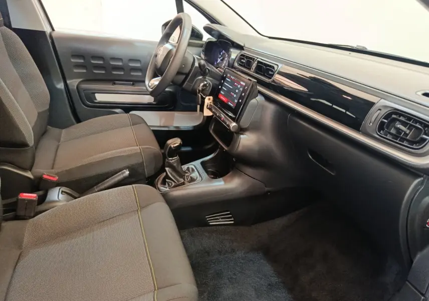 Intérieur de la Citroën C3 PureTech 83 2024, vue côté conducteur, tableau de bord noir avec écran tactile central.