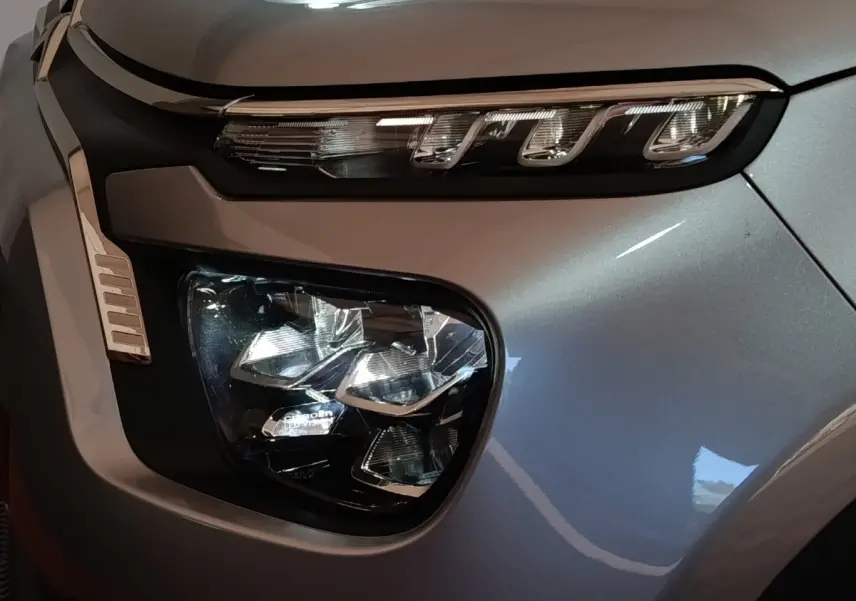 Gros plan sur le phare avant droit gris foncé d'une Citroën C3 2024 avec signature lumineuse LED distinctive.