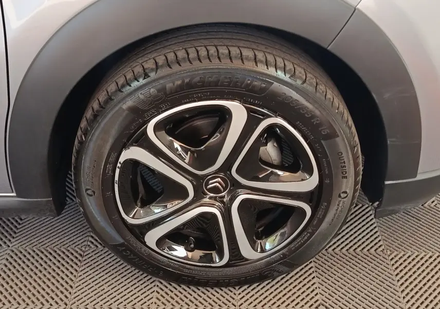 Gros plan sur la roue avant droite d'une Citroën C3 gris foncé, avec jante alliage noire et argentée au design moderne.