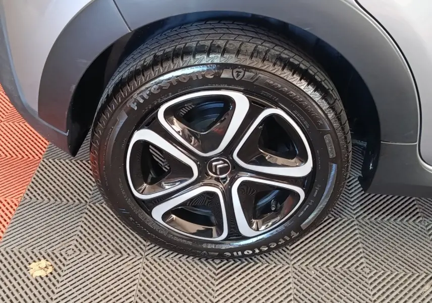 Gros plan sur la roue avant droite d'une Citroën C3 gris foncé avec jante noire et inserts argentés.