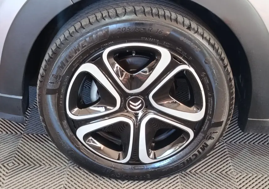 Gros plan sur la roue avant droite d'une Citroën C3 gris foncé avec jante alliage noire et argentée au design moderne.
