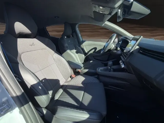 Intérieur de la Renault Clio Esprit Alpine E-Tech 2025, vue côté droit, sièges gris clair avec logo Alpine et écran tactile central.