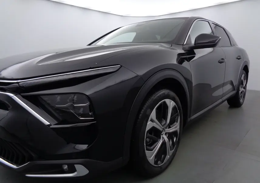 Vue 3/4 avant droit d'une Citroën C5 X noire métallisée avec phares LED et jantes bi-ton modernes.