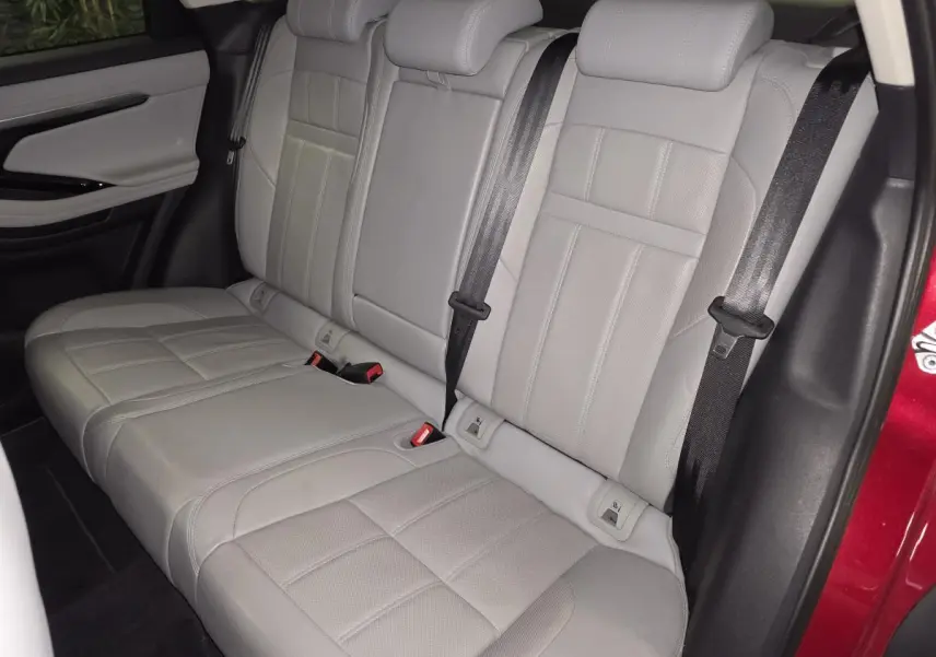 Vue intérieure des sièges arrière en cuir gris clair du Range Rover Evoque rouge, avec ceintures de sécurité visibles.