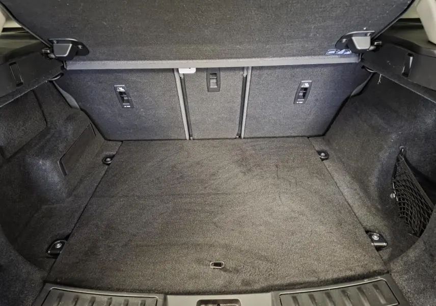 Coffre spacieux vu de l'intérieur, revêtement noir, du Range Rover Evoque rouge 2019 avec banquette arrière rabattue.