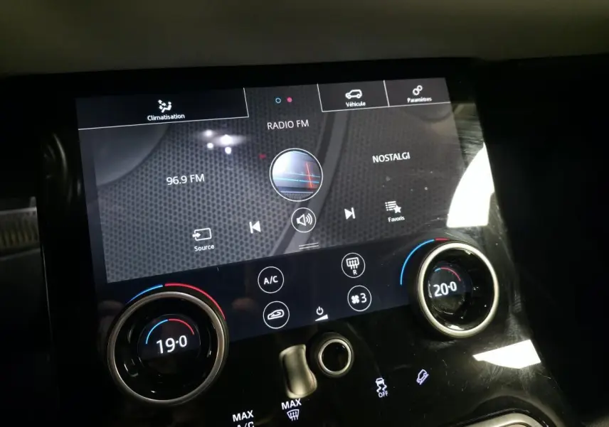 Gros plan sur la console centrale tactile du Range Rover Evoque rouge, affichant la radio et la climatisation bi-zone.