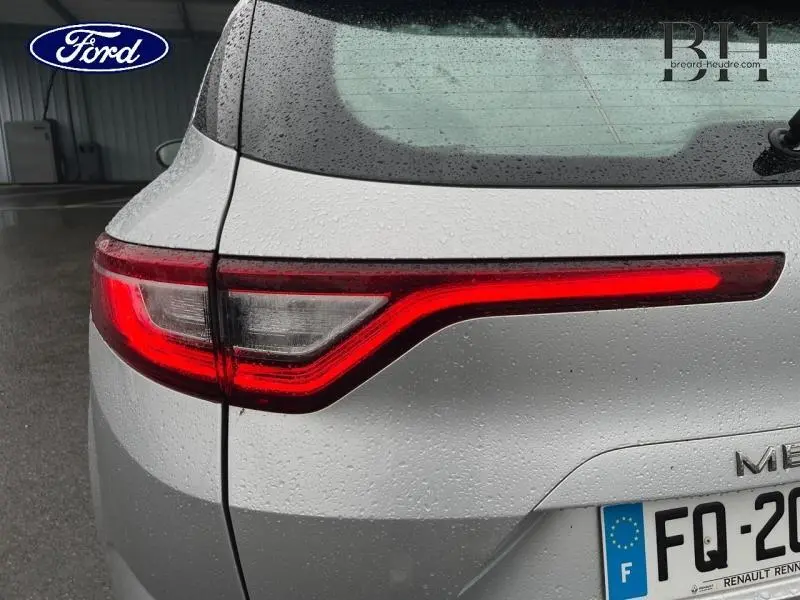 Gros plan sur le feu arrière gauche rouge allumé d'une Renault Mégane Break gris platine sous la pluie.