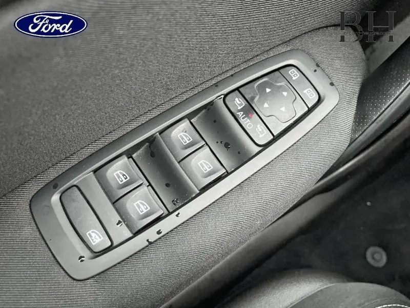 Gros plan sur les commandes électriques des vitres et rétroviseurs sur la porte côté conducteur, finition tissu gris.