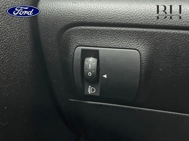 Commande de réglage de l'inclinaison des phares sur tableau de bord noir, intérieur d'une Renault Mégane Break gris platine.