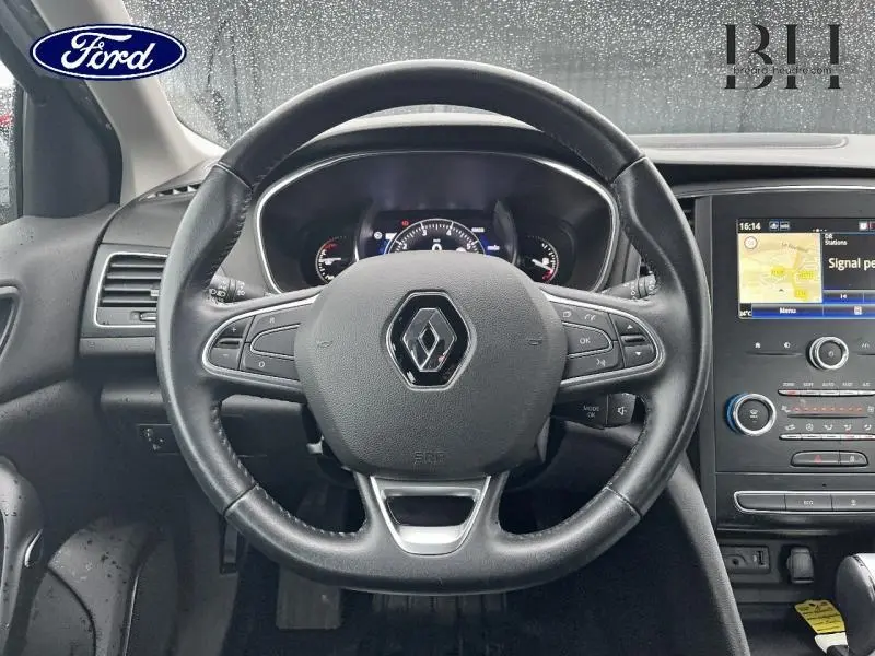 Vue centrée sur le volant en cuir noir de la Renault Mégane Break gris platine, avec tableau de bord et écran tactile visibles.