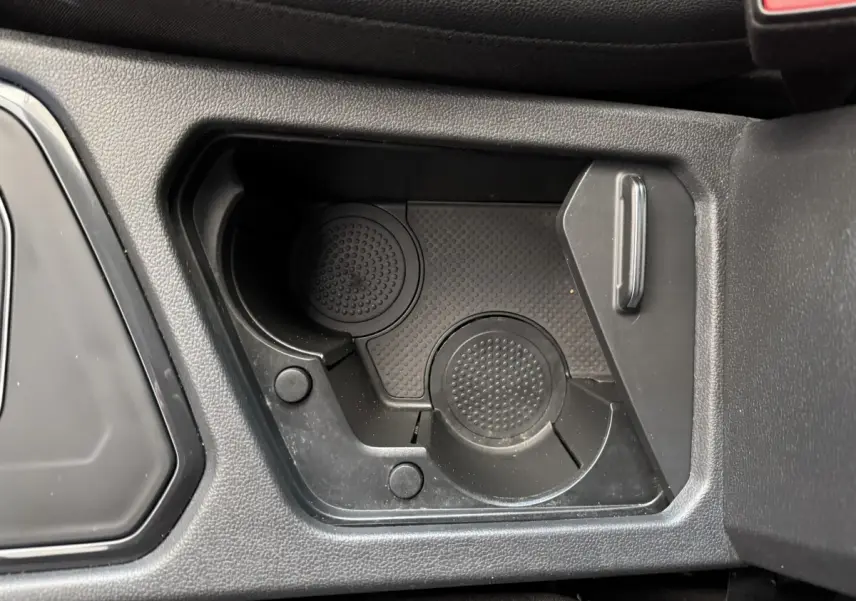 Gros plan sur le porte-gobelets noir intégré au console centrale du Volkswagen Tiguan Allspace gris foncé.
