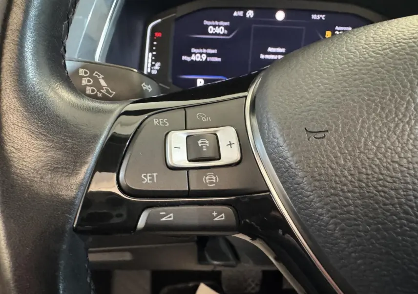 Gros plan sur les commandes du volant cuir noir du Volkswagen Tiguan Allspace 2019, avec affichage numérique en arrière-plan.