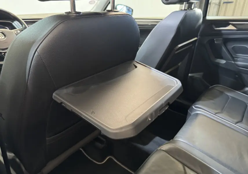 Vue intérieure côté droit du Volkswagen Tiguan Allspace 2019, tablette rabattable sur siège avant noir en cuir.