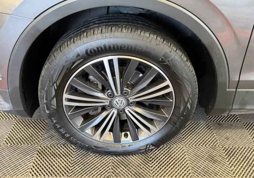 Gros plan sur la roue avant droite d'un Volkswagen Tiguan Allspace gris foncé avec jante alliage distinctive.