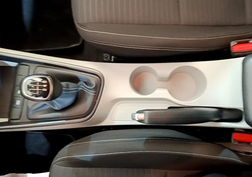 Vue plongeante sur la console centrale beige et noire avec levier de vitesse manuel et frein à main d'une Hyundai i20 gris clair.