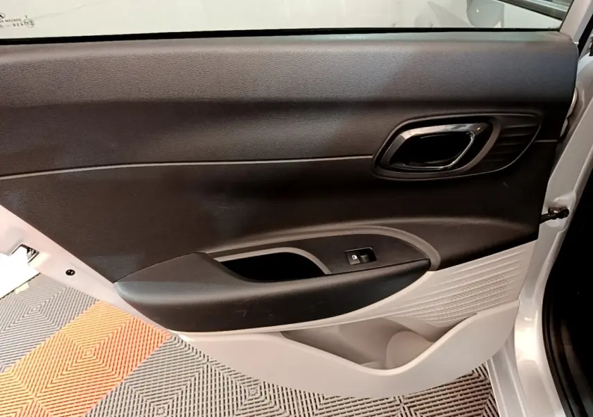 Vue intérieure du panneau de porte avant droit de la Hyundai i20 gris clair, avec commande de vitre électrique.