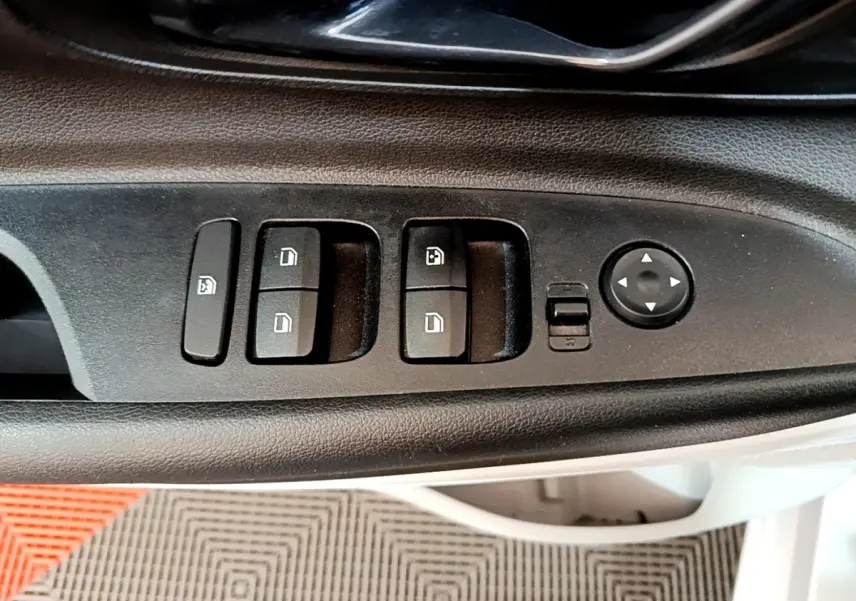 Gros plan sur les commandes de lève-vitres et rétroviseurs côté conducteur d'une Hyundai i20 gris clair 2022.