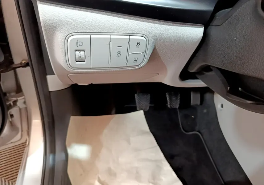 Vue intérieure côté conducteur du tableau de commandes gris clair avec réglage phares et contrôle traction d’une Hyundai i20 2022.