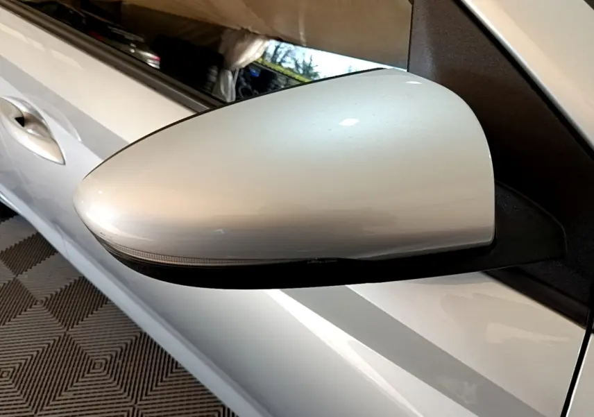 Gros plan sur le rétroviseur côté gauche gris clair de la Hyundai i20 2022, avec la portière visible en arrière-plan.