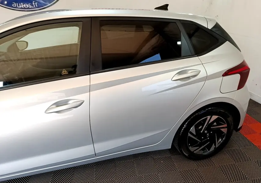 Vue latérale droite d'une Hyundai i20 gris clair 2022 avec jantes noires et vitres teintées.