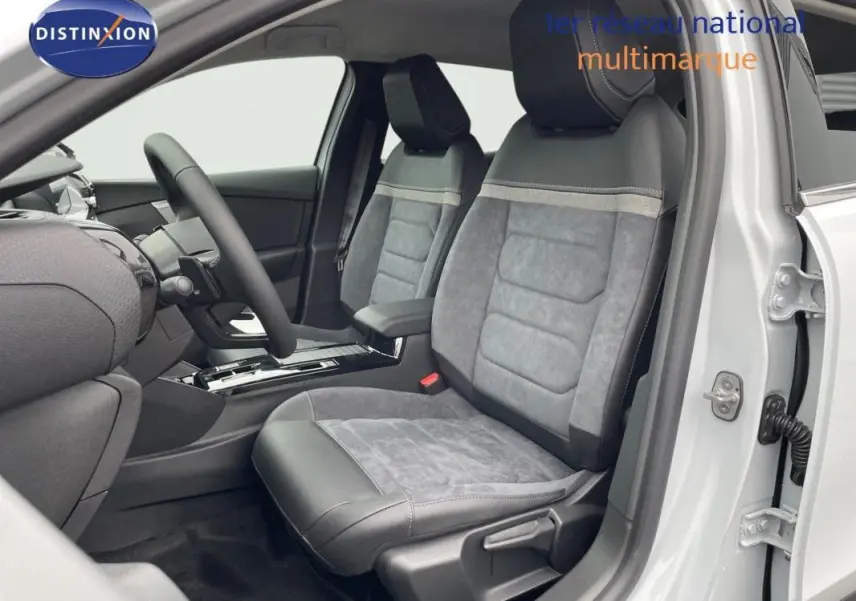 Vue intérieure côté conducteur de la Citroën C4 blanche 2024, sièges en tissu gris et cuir avec console centrale moderne.