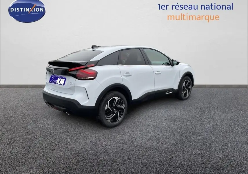 Vue 3/4 arrière droite d'une Citroën C4 blanche 2024 avec jantes aluminium et toit noir contrasté.