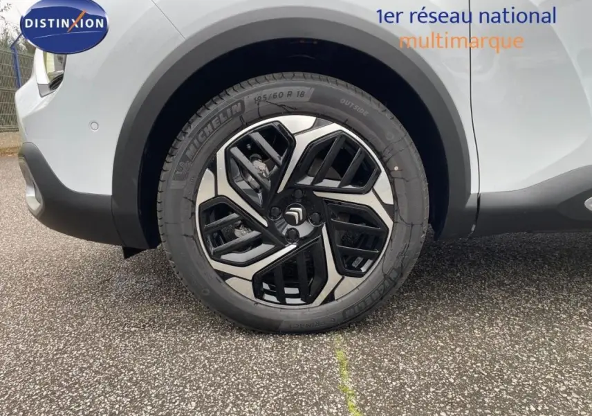 Gros plan sur la roue avant droite d'une Citroën C4 blanche 2024 avec jante aluminium au design moderne.