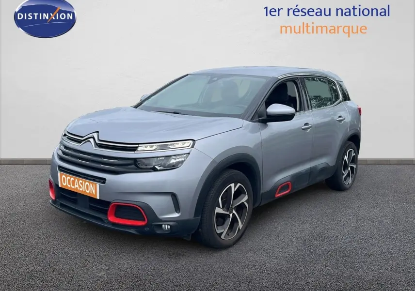 Citroën C5 Aircross gris clair métal en 3/4 avant droit avec détails rouges sur boucliers et bas de caisse.