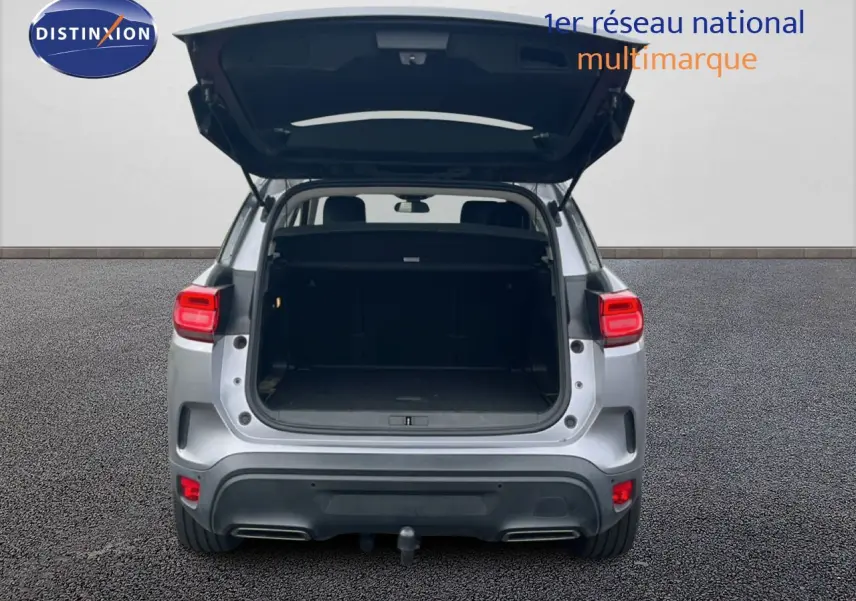 Vue arrière d'un Citroën C5 Aircross gris clair métal avec coffre ouvert, mettant en valeur l'espace de chargement.
