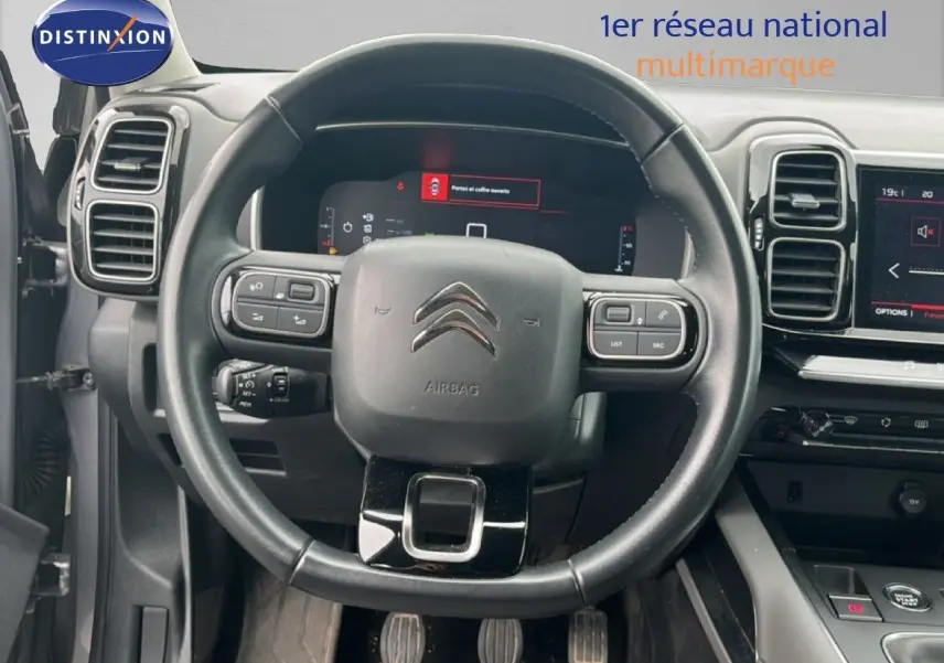 Vue centrée sur le volant noir et le tableau de bord numérique d'une Citroën C5 Aircross gris clair 2020 essence.