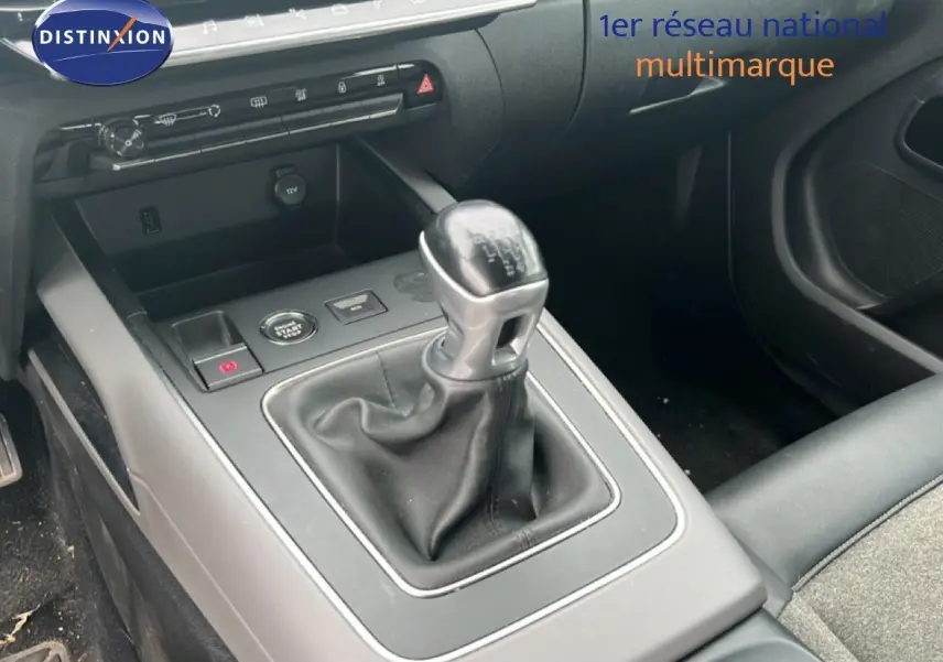 Gros plan sur la console centrale du Citroën C5 Aircross gris clair, mettant en valeur le levier de vitesses manuel et les commandes environnantes.