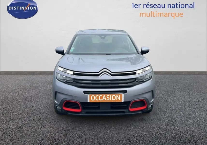 Vue frontale d'un Citroën C5 Aircross gris clair métal avec détails rouges sur le pare-chocs et feux LED allumés.