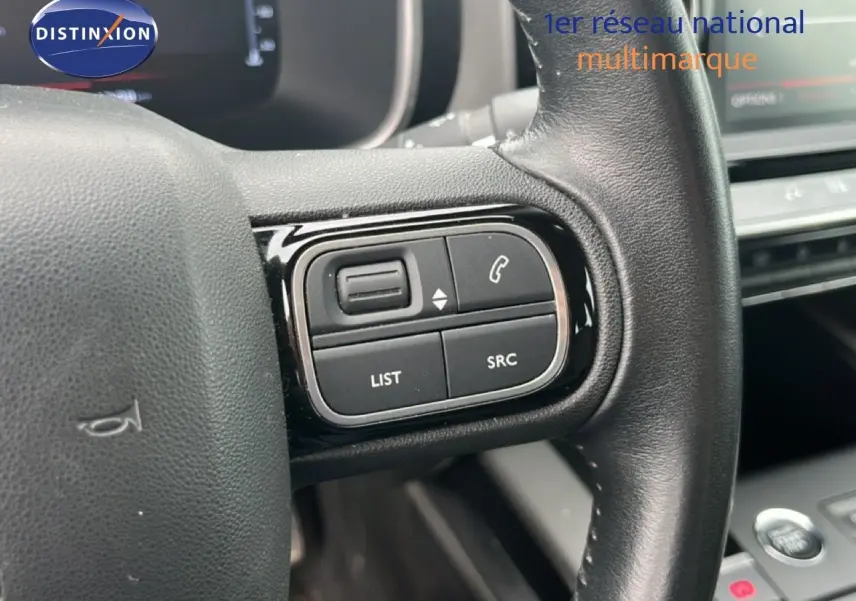 Gros plan sur les commandes multimédia au volant d’un Citroën C5 Aircross gris clair, intérieur 2020.